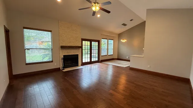 a view of an empty room with wooden floor fireplace and a window