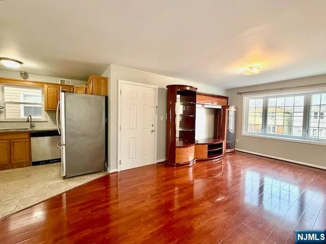 a view of an empty room with window and wooden floor