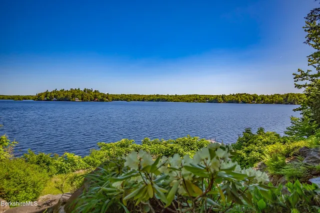 a kitchen with stainless steel appliances a stove a sink a dining table and chairs with wooden floor