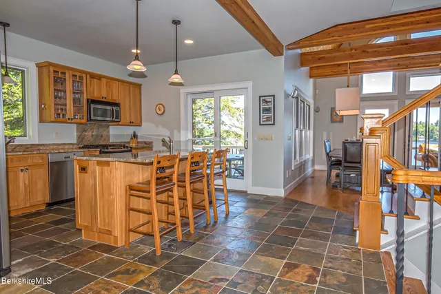 a kitchen with stainless steel appliances a sink a stove a refrigerator cabinets and dining table