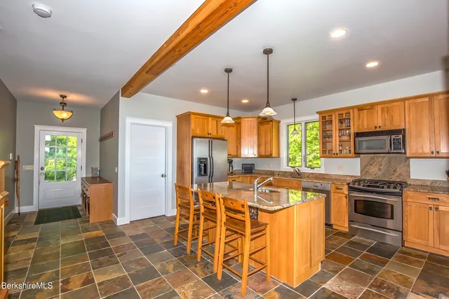 a kitchen with stainless steel appliances granite countertop a stove top oven a refrigerator and cabinets