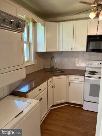 a kitchen with granite countertop white cabinets and white appliances