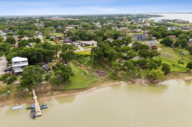 an aerial view of a houses with a yard and lake view