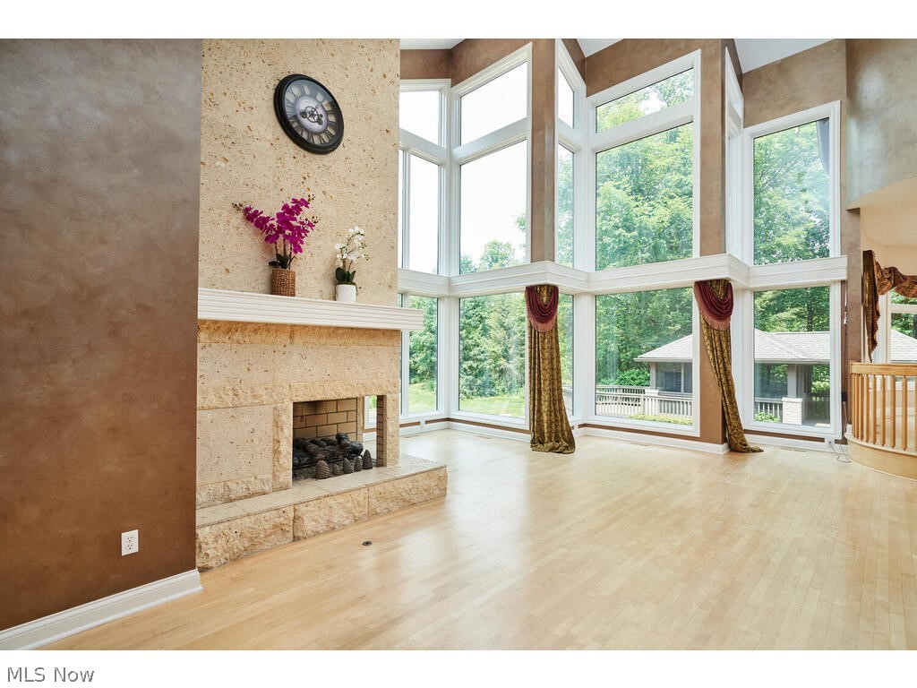 7786 Valley View Road Hudson, OH 44236 - Photo 9 of 50 Unfurnished living room with a high ceiling, plenty of natural light, a premium fireplace, and hardwood / wood-style flooring