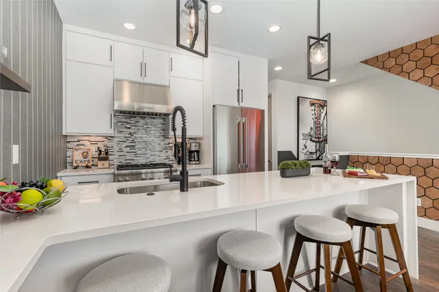 a kitchen with granite countertop a sink chairs and refrigerator