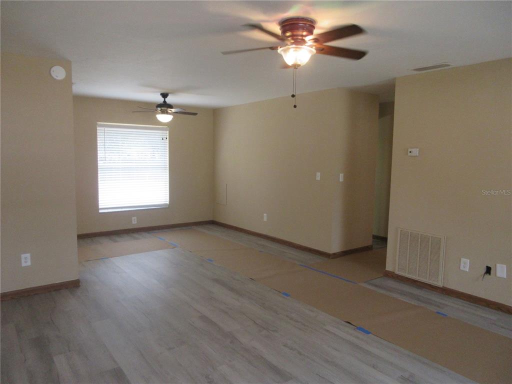 2601 Southeast 175th Terrace Road Silver Springs, FL 34488 - Photo 19 of 87 an empty room with wooden floor chandelier fan and windows