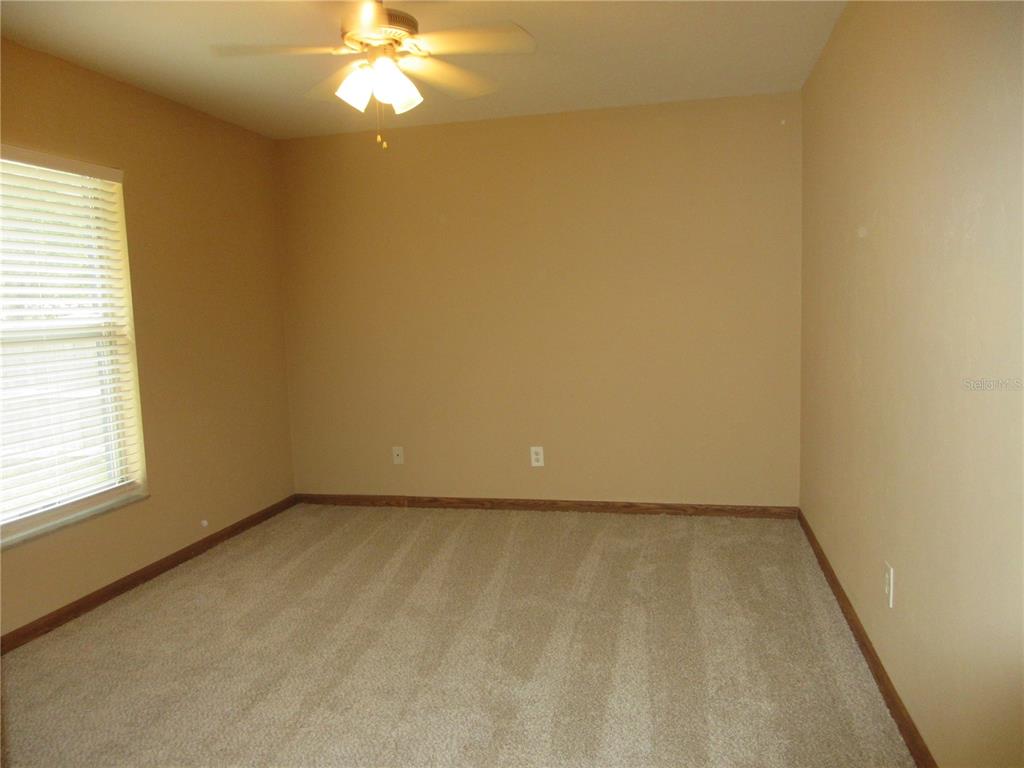2601 Southeast 175th Terrace Road Silver Springs, FL 34488 - Photo 49 of 87 an empty room with a chandelier fan and windows
