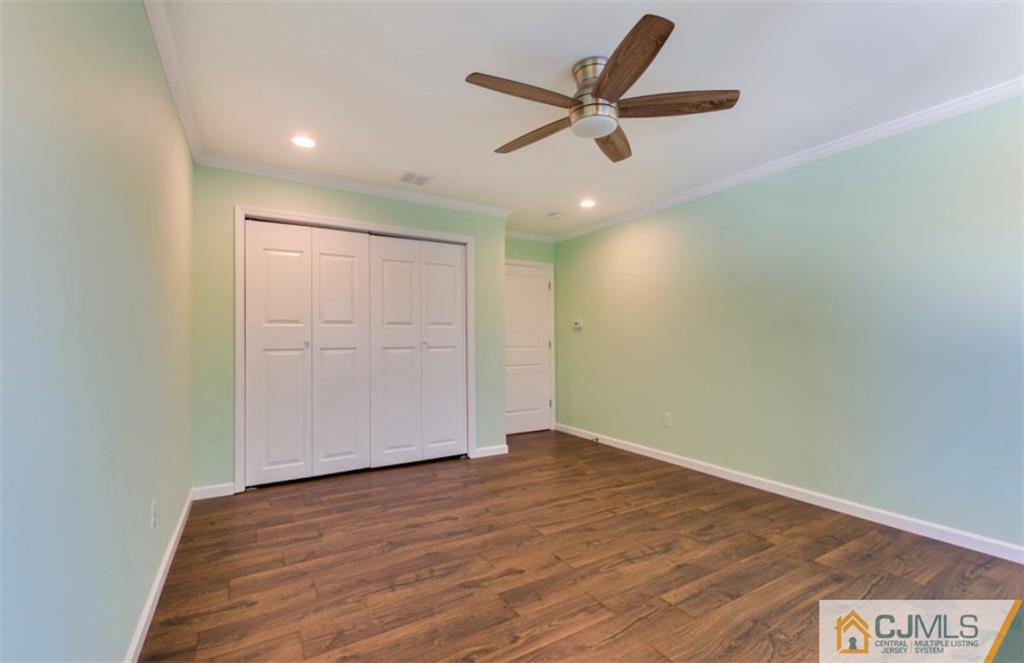10 Markham Road Edison, NJ 08817 - Photo 19 of 23 an empty room with wooden floor and a ceiling fan