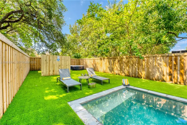 a view of a patio with table and chairs and floor to ceiling window with wooden fence
