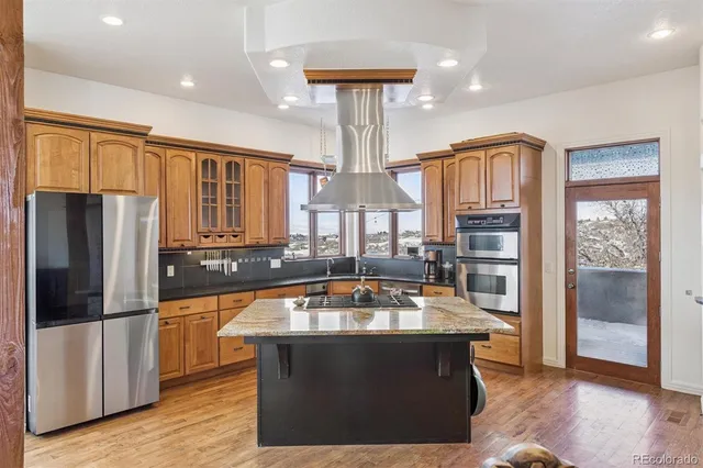 a kitchen with stainless steel appliances granite countertop a refrigerator a stove and a sink