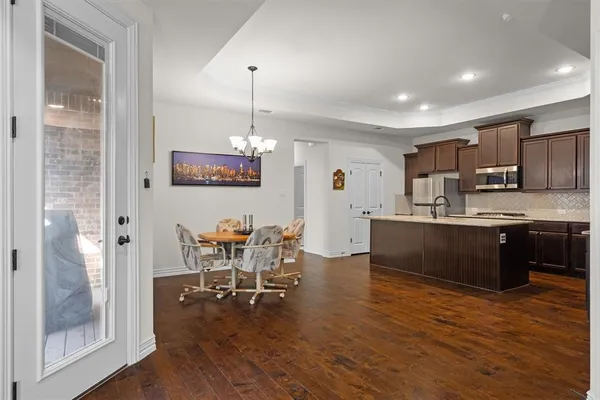 a kitchen with stainless steel appliances kitchen island granite countertop a refrigerator a stove a sink a dining table and chairs with wooden floor