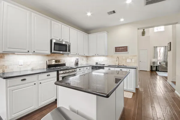a kitchen with kitchen island granite countertop a sink a counter space stainless steel appliances and cabinets