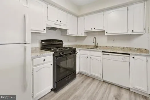 a kitchen with granite countertop white cabinets and white appliances