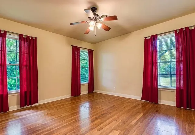 a view of an empty room with wooden floor and a window