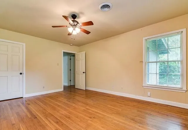 a view of an empty room with wooden floor and a window