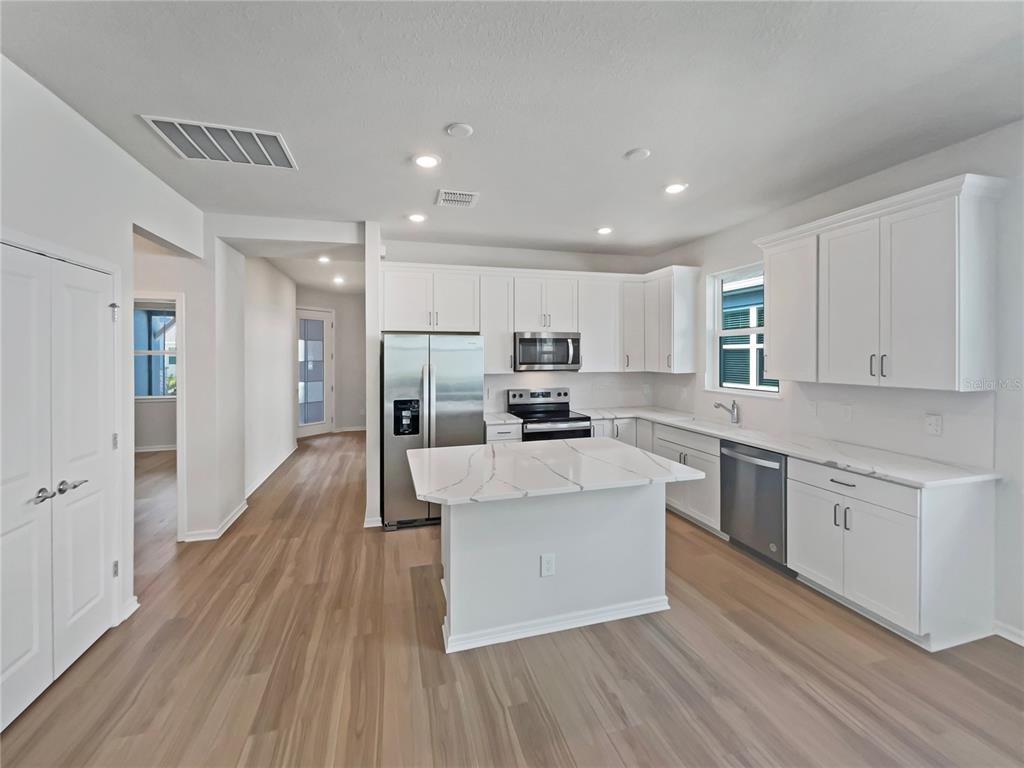 1909 Spring Shower Circle Kissimmee, FL 34744 - Photo 2 of 32 a large kitchen with stainless steel appliances refrigerator a stove top oven with wooden floors