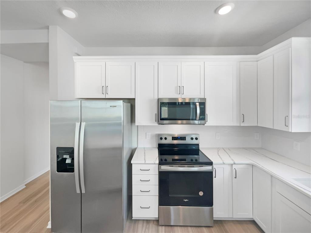 1909 Spring Shower Circle Kissimmee, FL 34744 - Photo 21 of 32 a kitchen with a refrigerator stove and white cabinets