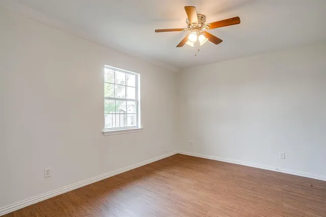 an empty room with a window and a fan