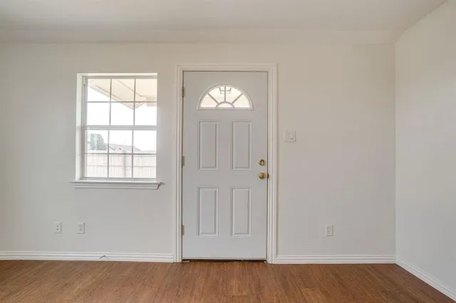an empty room with wooden floor and window
