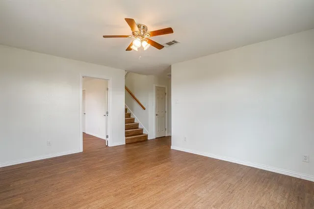 a view of an empty room with wooden floor and stairs