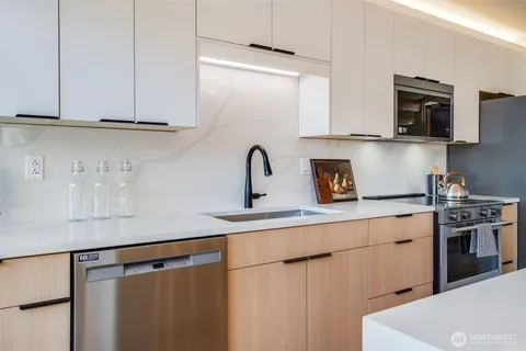 a kitchen with stainless steel appliances a sink dishwasher a refrigerator and cabinets with wooden floor