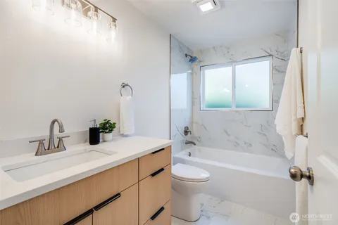 a bathroom with a granite countertop sink a toilet and shower
