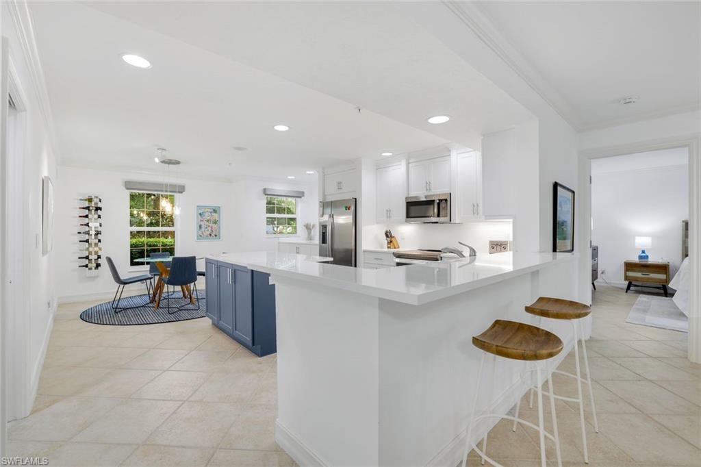 376 3rd Street South, Unit 102 Naples, FL 34102 - Photo 6 of 17 Kitchen featuring a kitchen bar, recessed lighting, ornamental molding, white cabinets, and hanging light fixtures