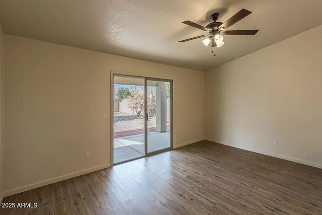 an empty room with wooden floor and a chandelier fan