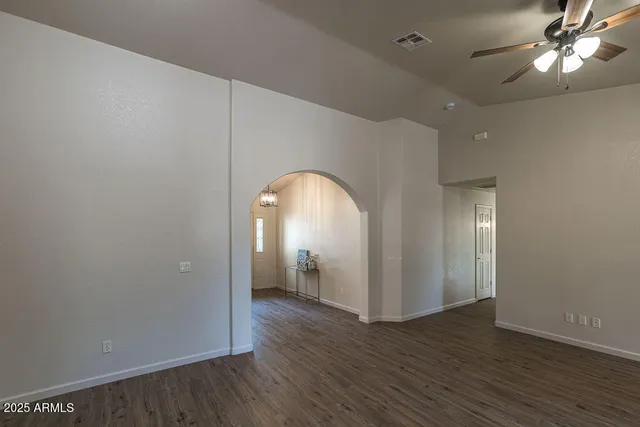 an empty room with wooden floor fan and windows