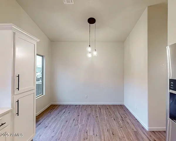 a view of a kitchen with refrigerator and wooden floor