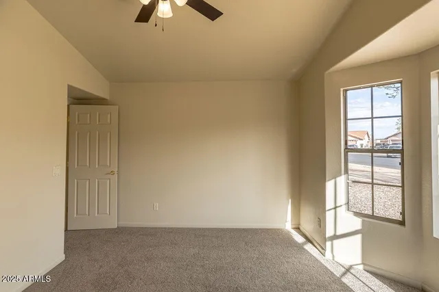 an empty room with chandelier fan and windows