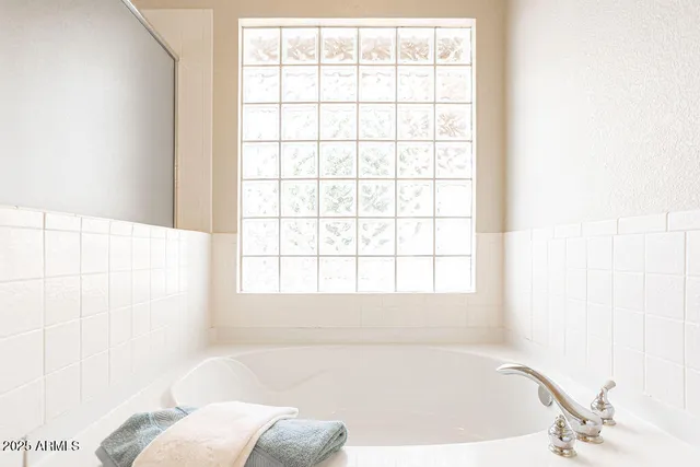 an empty room with chandelier fan and windows