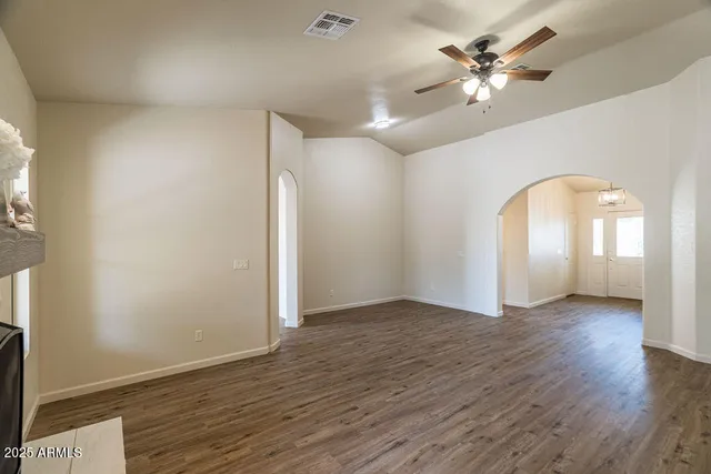 an empty room with wooden floor and ceiling fan