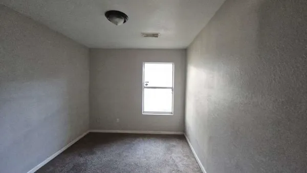 an empty room with a window and closet area
