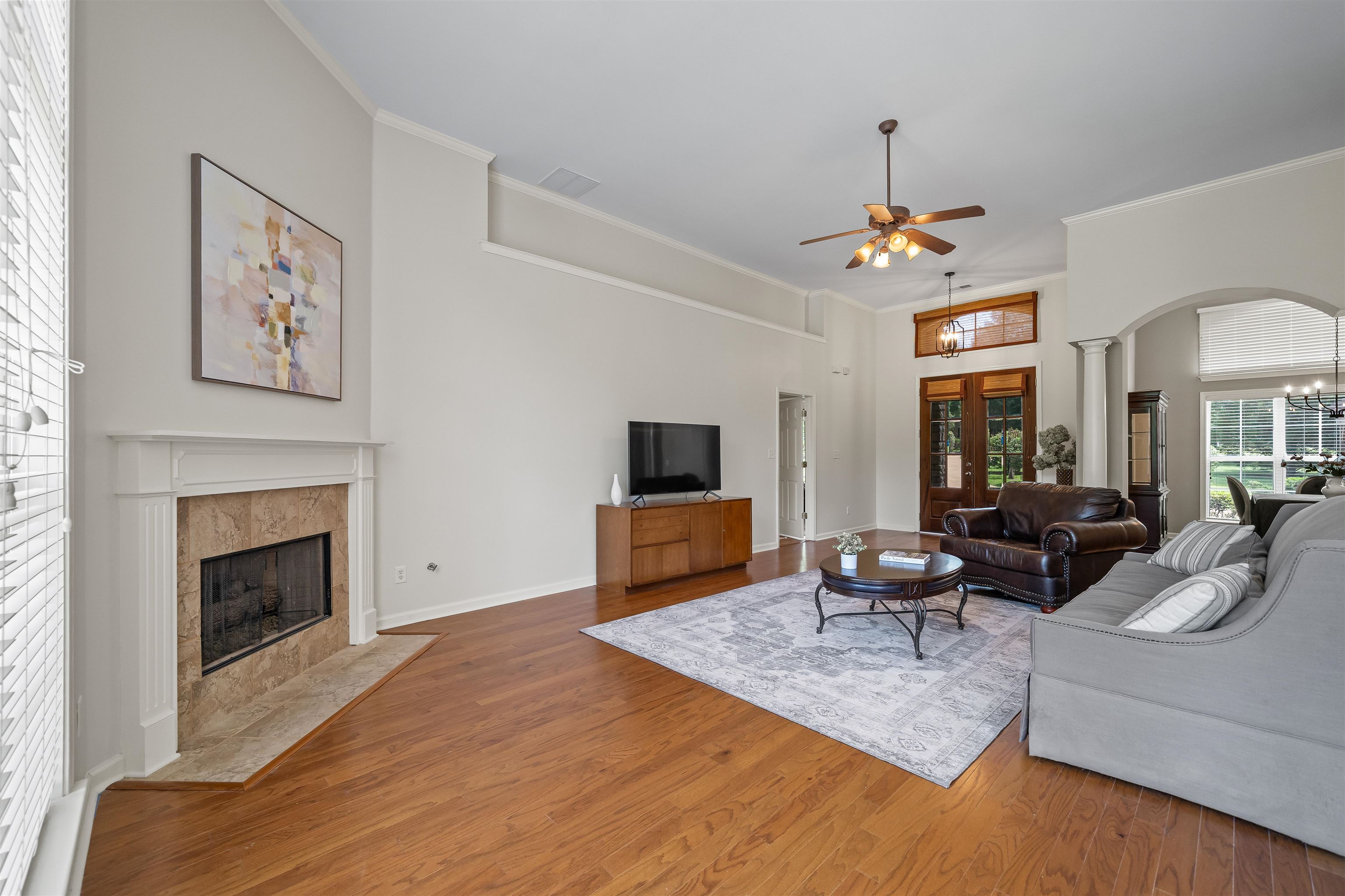 5035 Brian Ridge Road Arlington, TN 38002 - Photo 12 of 40 Spacious living area featuring wood-finish flooring, a corner fireplace with a white mantel and stone surround, and an arched entry