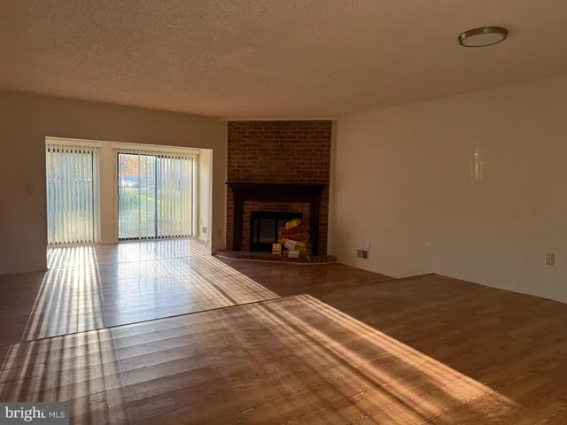 an empty room with wooden floor fireplace and windows