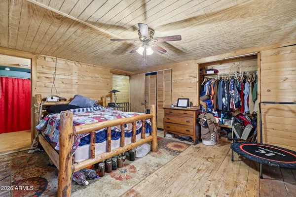 a bedroom with a bed a dresser and wooden floor
