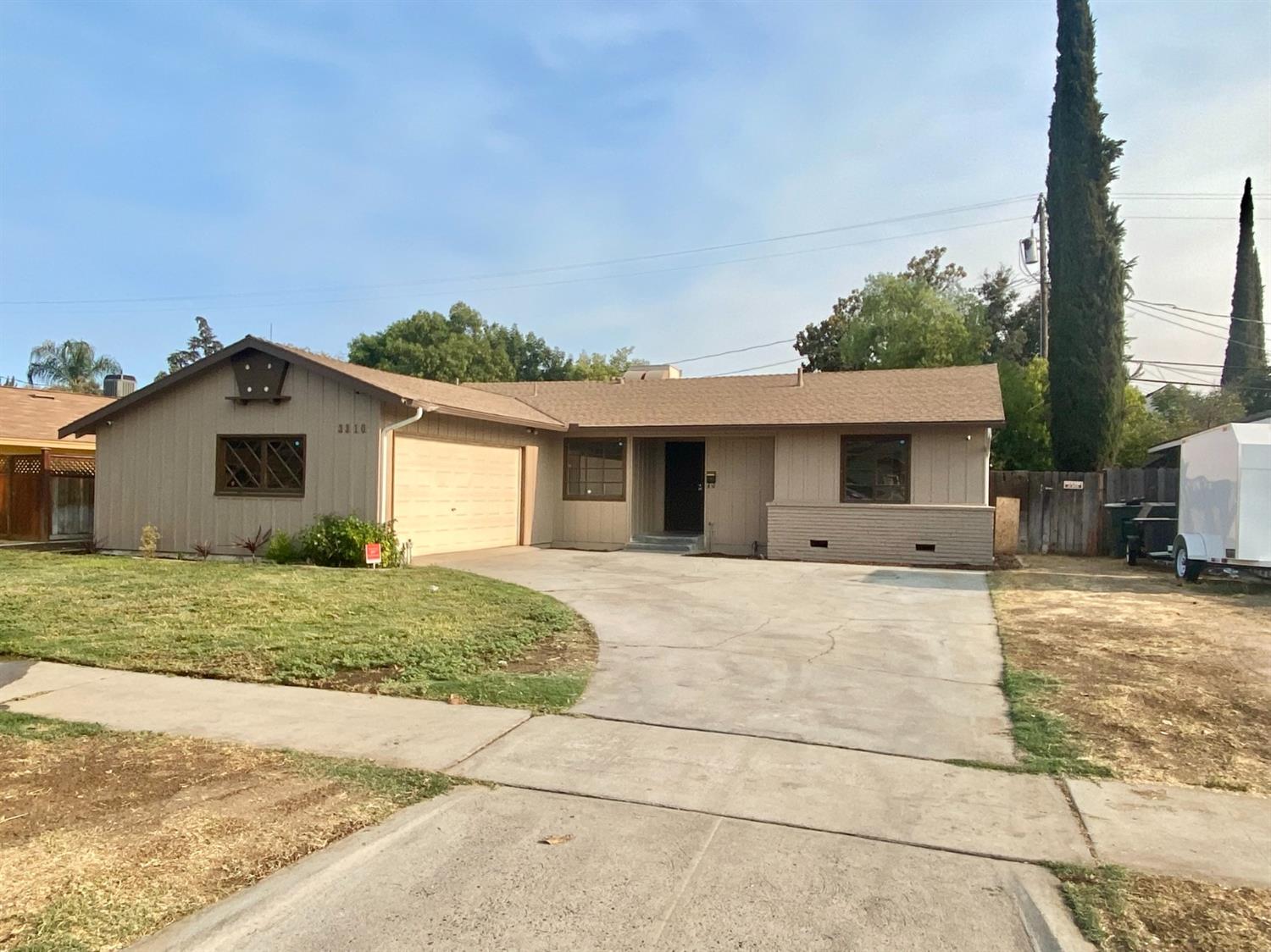 3310 East Hampton Way Fresno, CA 93726 - Photo 1 of 18 a front view of a house with a yard and garage