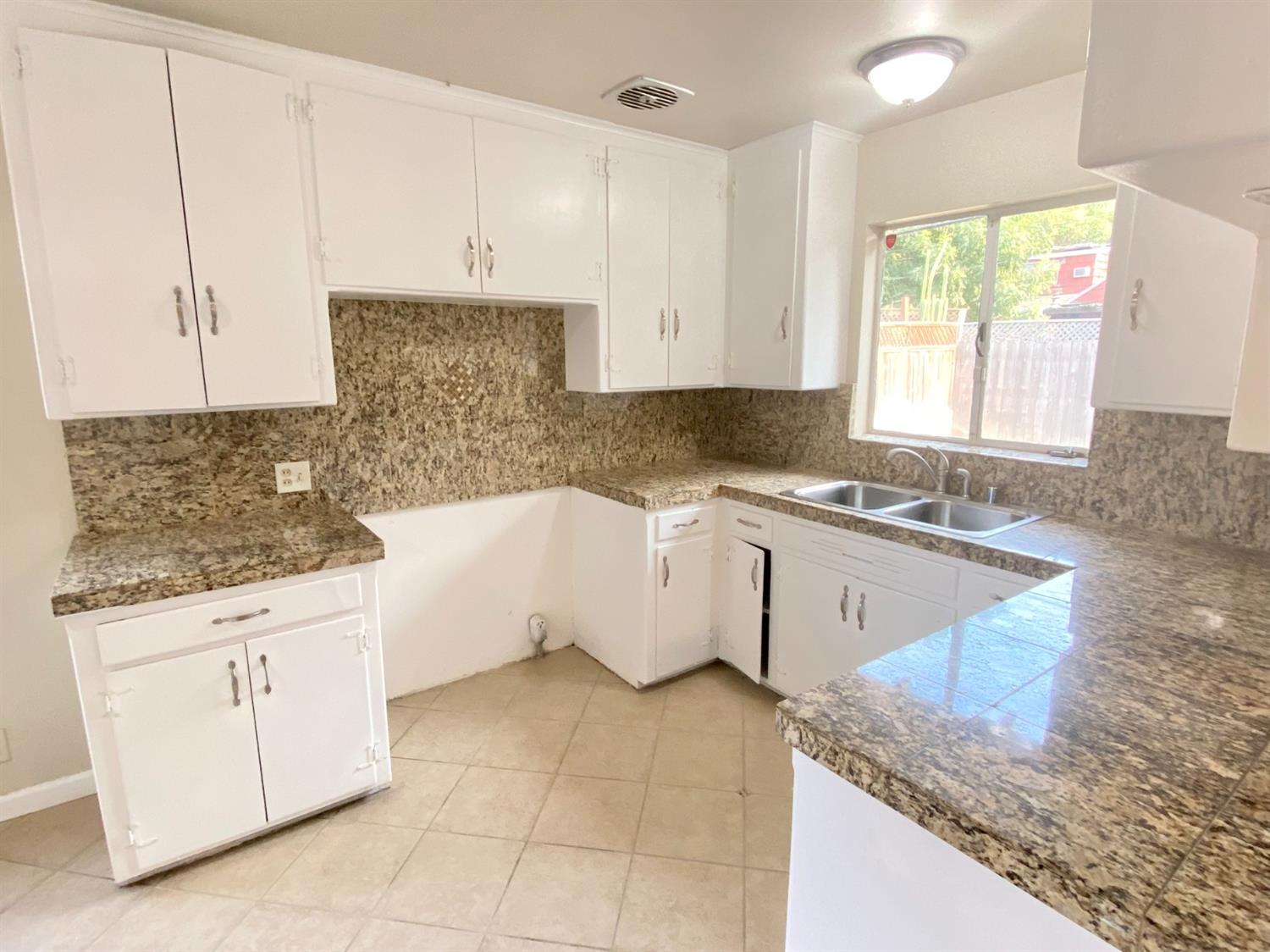 3310 East Hampton Way Fresno, CA 93726 - Photo 3 of 18 a kitchen with granite countertop a sink a stove and cabinets
