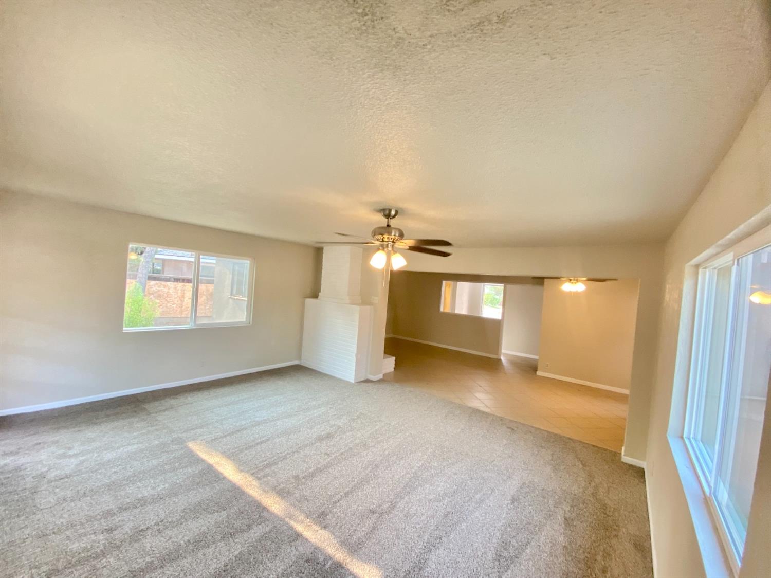 3310 East Hampton Way Fresno, CA 93726 - Photo 6 of 18 an empty room with windows and fireplace