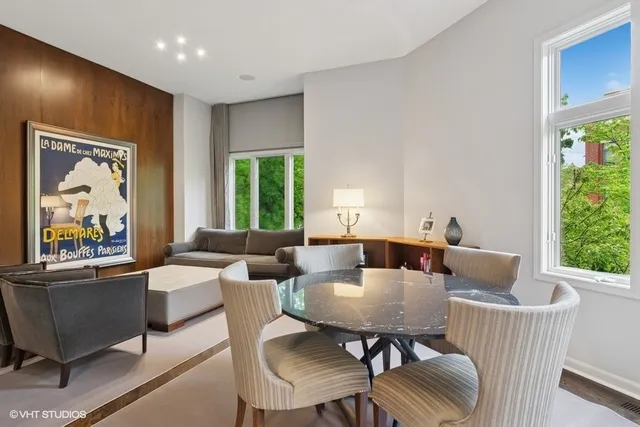 a view of a dining room with furniture a large window and wooden floor