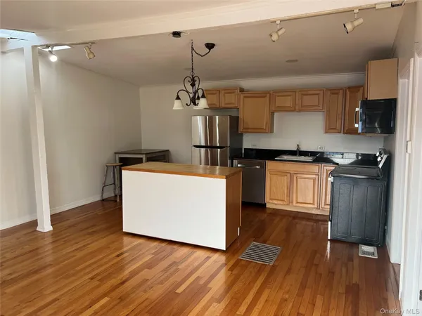a kitchen with kitchen island wooden floors and stainless steel appliances