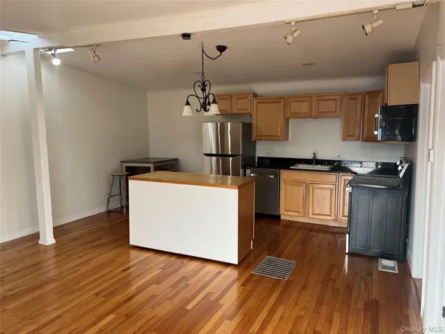 a kitchen with kitchen island wooden floors and stainless steel appliances