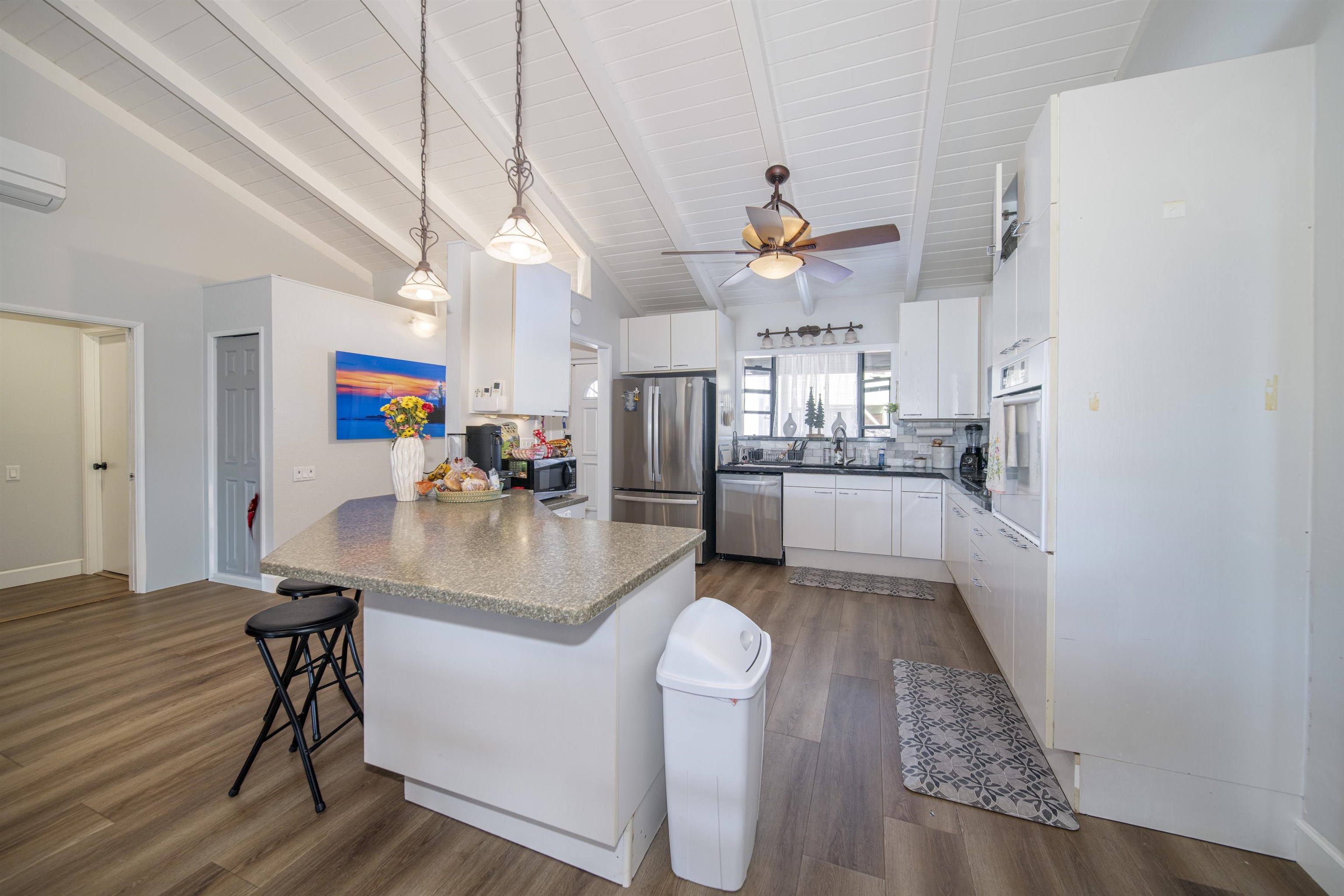 4996 Lower Honoapiilani Road Lahaina, HI 96761 - Photo 24 of 37 a kitchen with stainless steel appliances granite countertop a refrigerator a oven a sink a dining table and chairs with wooden floor