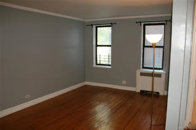 an empty room with wooden floor closet and windows