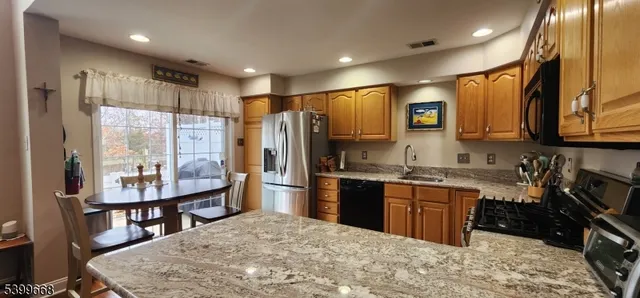 a kitchen with stainless steel appliances granite countertop a sink a stove and a wooden floors