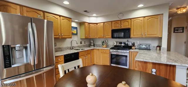 a kitchen with stainless steel appliances granite countertop a refrigerator a stove top oven a sink and dishwasher
