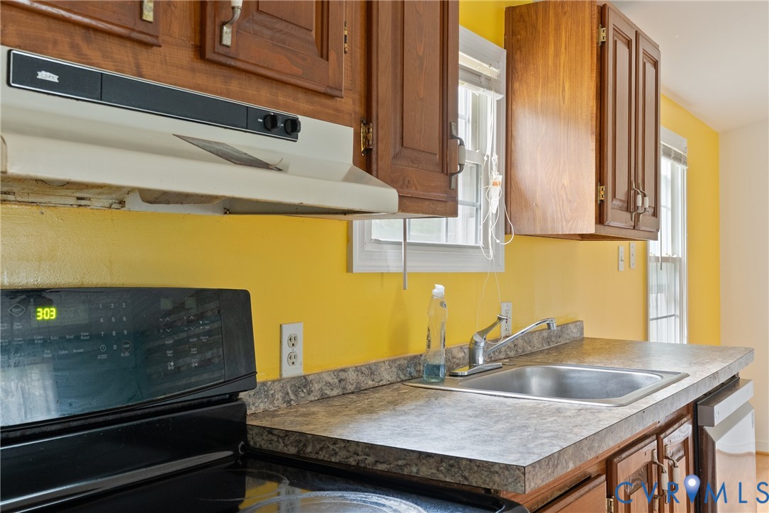 Kitchen with brown cabinetry, under cabinet range