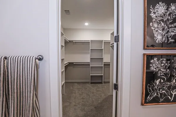 a walk in closet with wooden floor