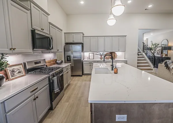 a kitchen with stainless steel appliances a stove a sink a microwave a refrigerator and cabinets